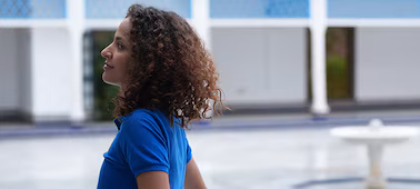 Example image of a woman walking along a bright courtyard corridor, looking towards the courtyard centre